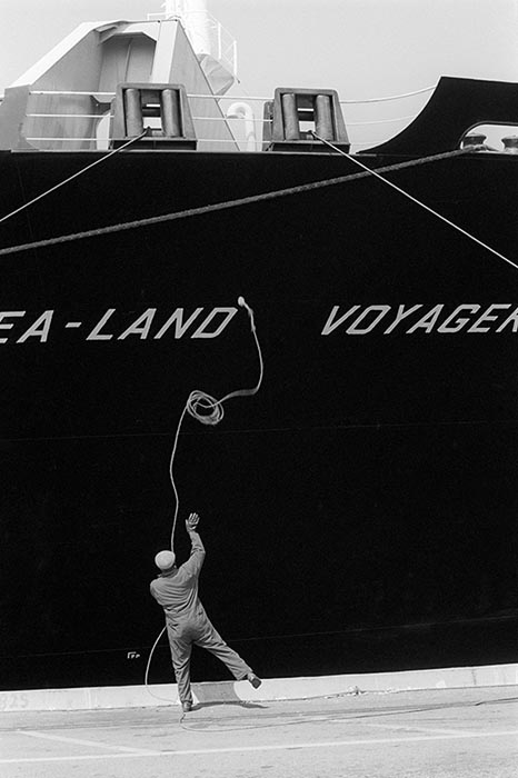 Worker throwing a rope to a ship