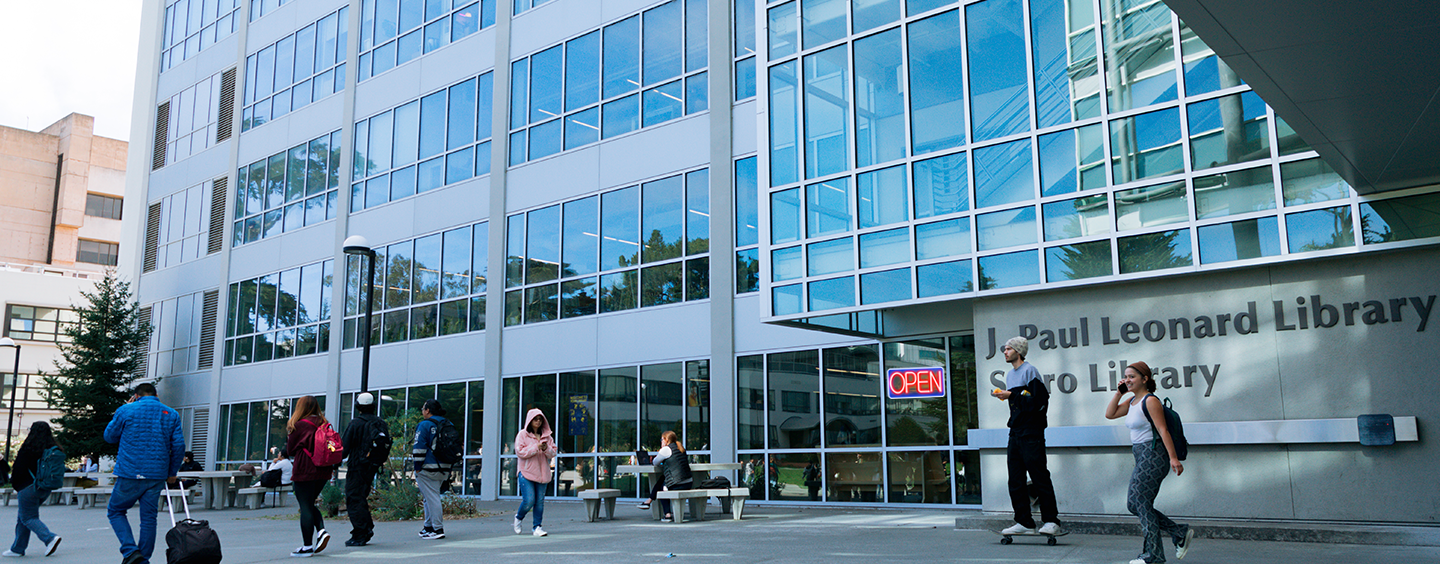 Students in front of the SF State Library with a neon OPEN sign in the window (photo illustration)