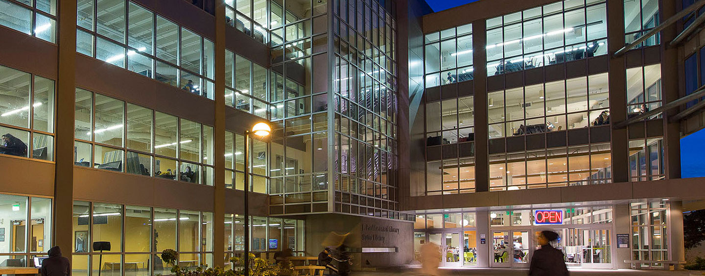 SF State Library after dark with a neon OPEN sign in the window (photo illustration)