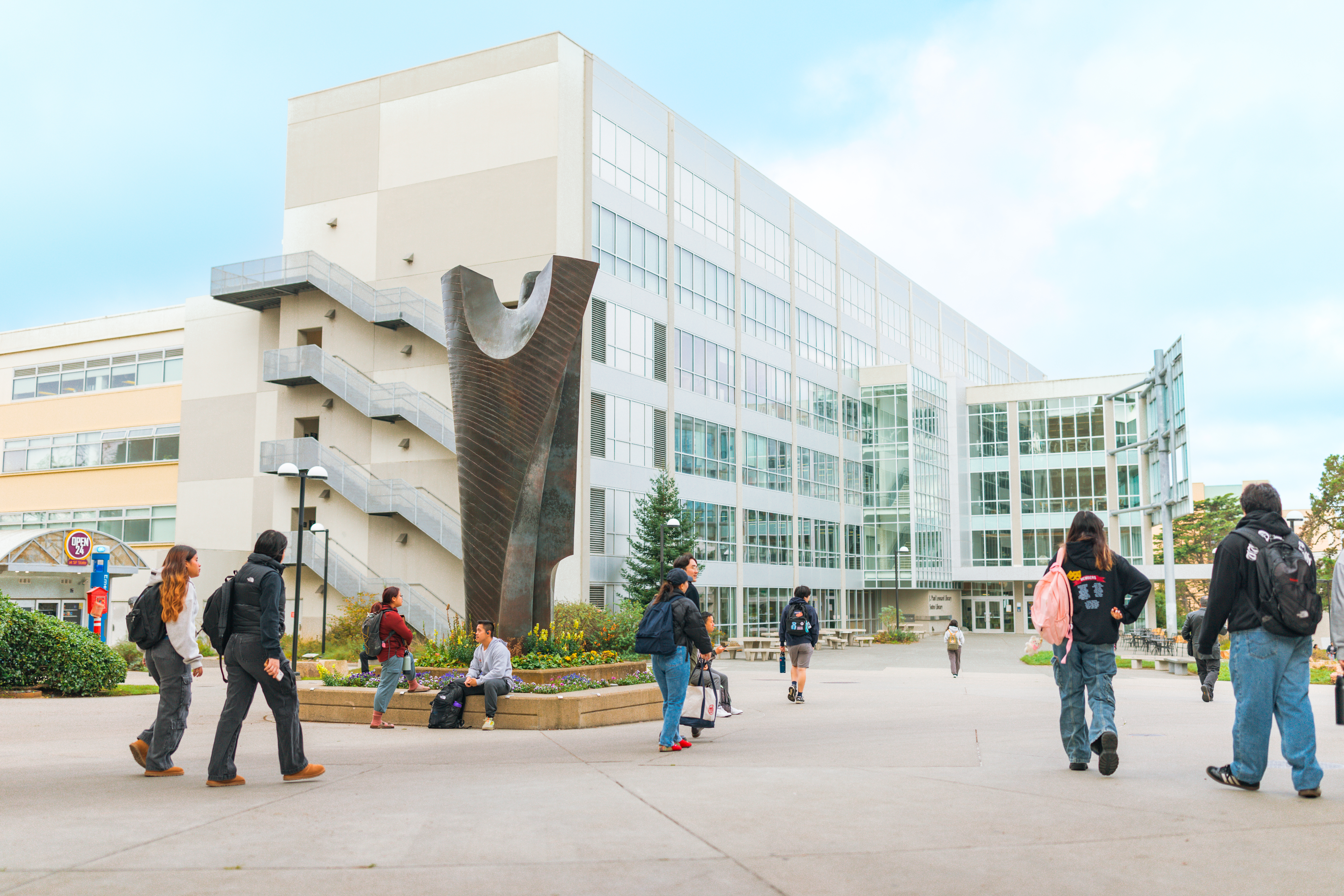 People walk toward the SFSU Library on a bright day