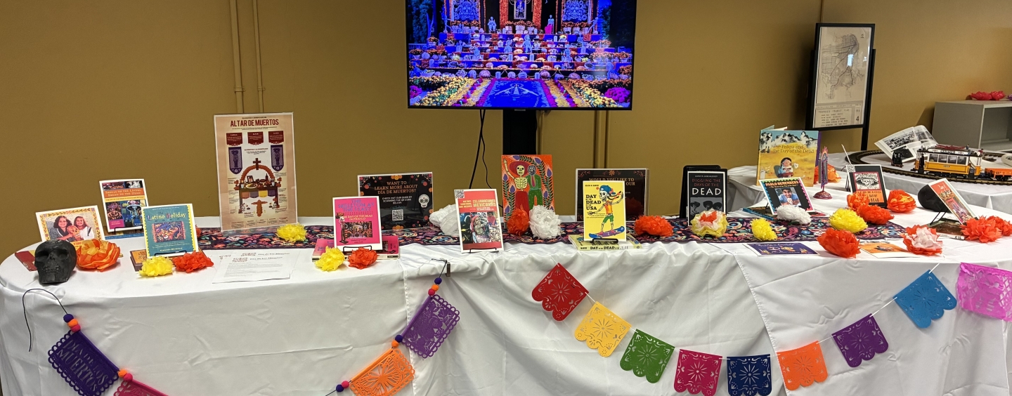 Books and materials on a table decorated with flowers and papel picado