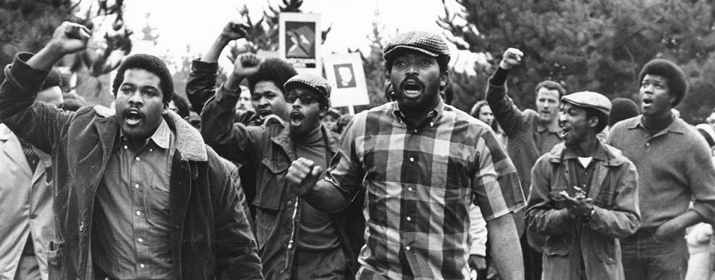 A group of mostly Black students chanting with raised fists and protest signs during the SF State Strike