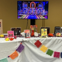 Books and materials on a table decorated with flowers and papel picado