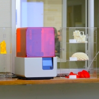 3D printing machines and plastic printed objects on a table