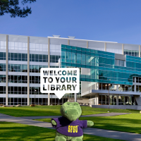 A small toy gator in an SFSU T-shirt says "Welcome to your Library"