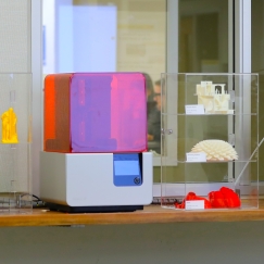 3D printing machines and plastic printed objects on a table