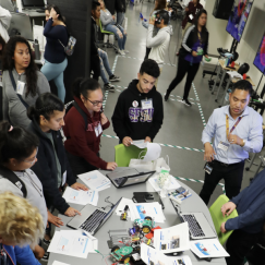 A crowd of people working on laptops and using VR equipment