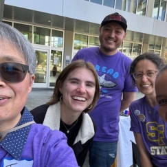 Five smiling people clustered together for a selfie