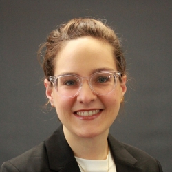 Zia's headshot, a smiling white woman with hair pulled back and clear glasses