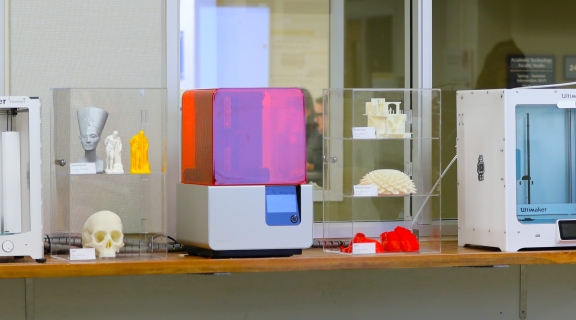 3D printing machines and plastic printed objects on a table