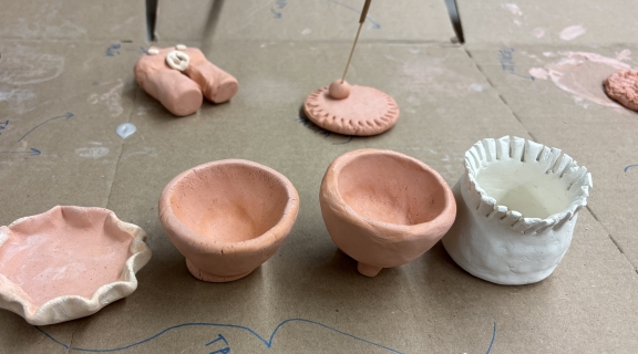 Small handmade clay pots and sculptures on cardboard