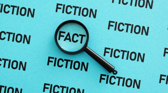 Magnifying glass on the word FACT surrounded by the word FICTION